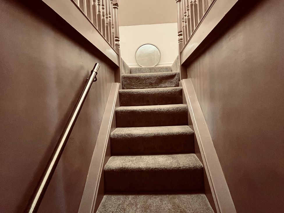 Stairs leading up with a handrail and a mirror at Horseshoe Cottage Macclesfield