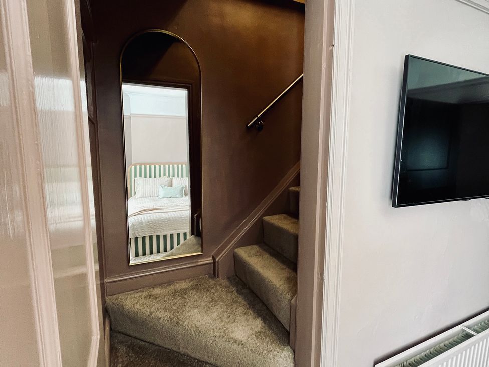 A staircase with a mirror and a television in a hallway at Horseshoe Cottage in Macclesfield