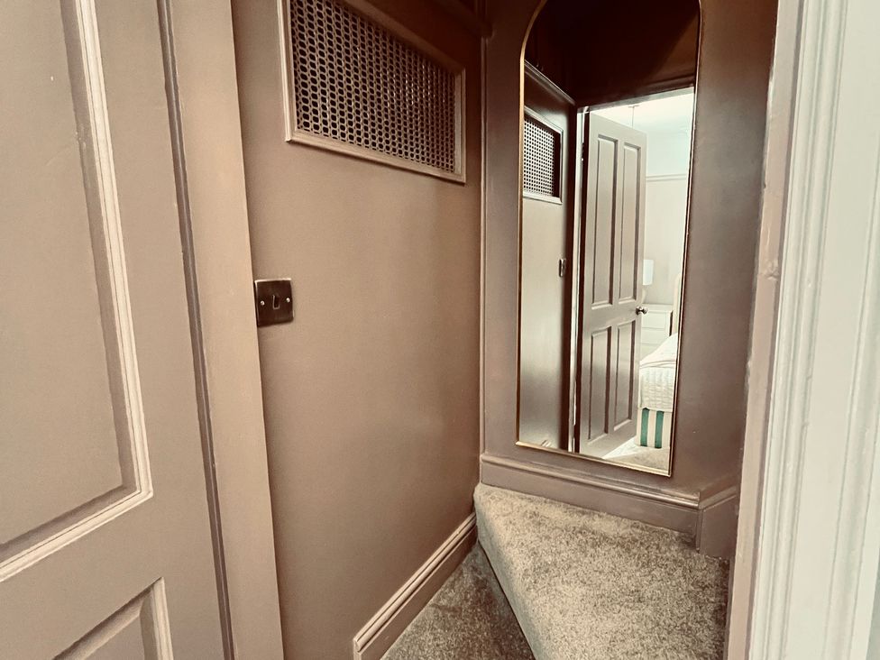 A hallway with a staircase and door at Horseshoe Cottage in Macclesfield