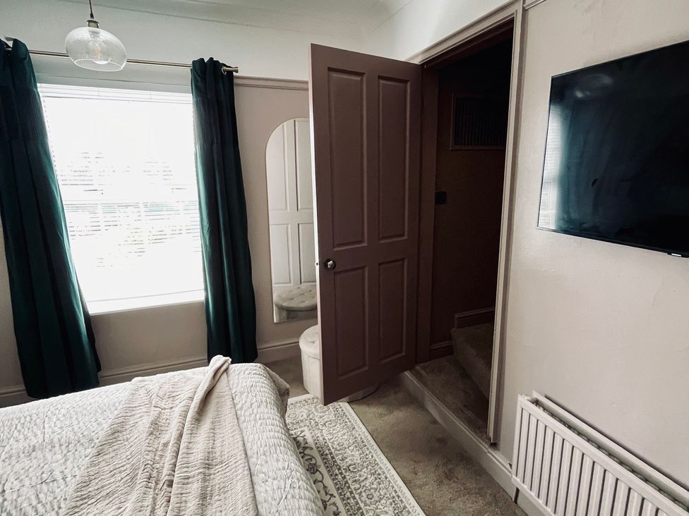 A bedroom with a window and a door at Horseshoe Cottage in Macclesfield