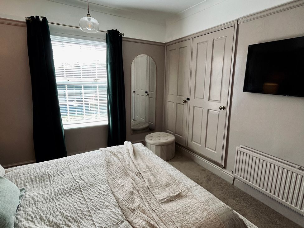 A bedroom with a bed, wardrobe, mirror, and television at Horseshoe Cottage in Macclesfield