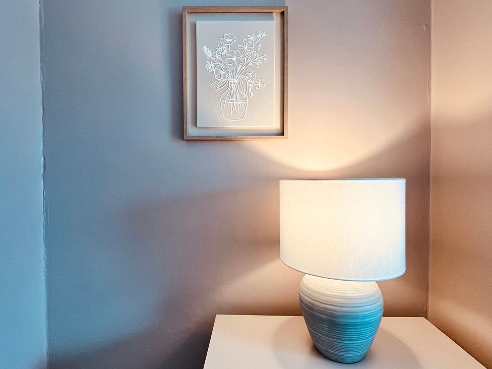A lamp on a table and artwork on the wall at Horseshoe Cottage in Macclesfield