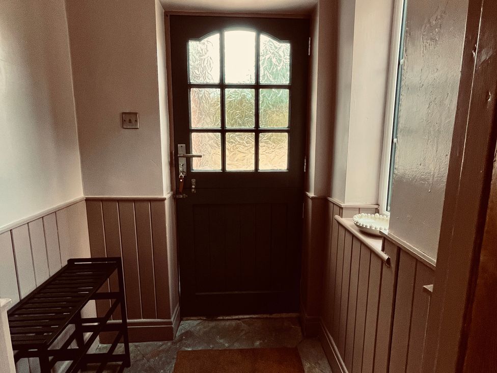 A hallway with a front door and a coat rack at Horseshoe Cottage in Macclesfield