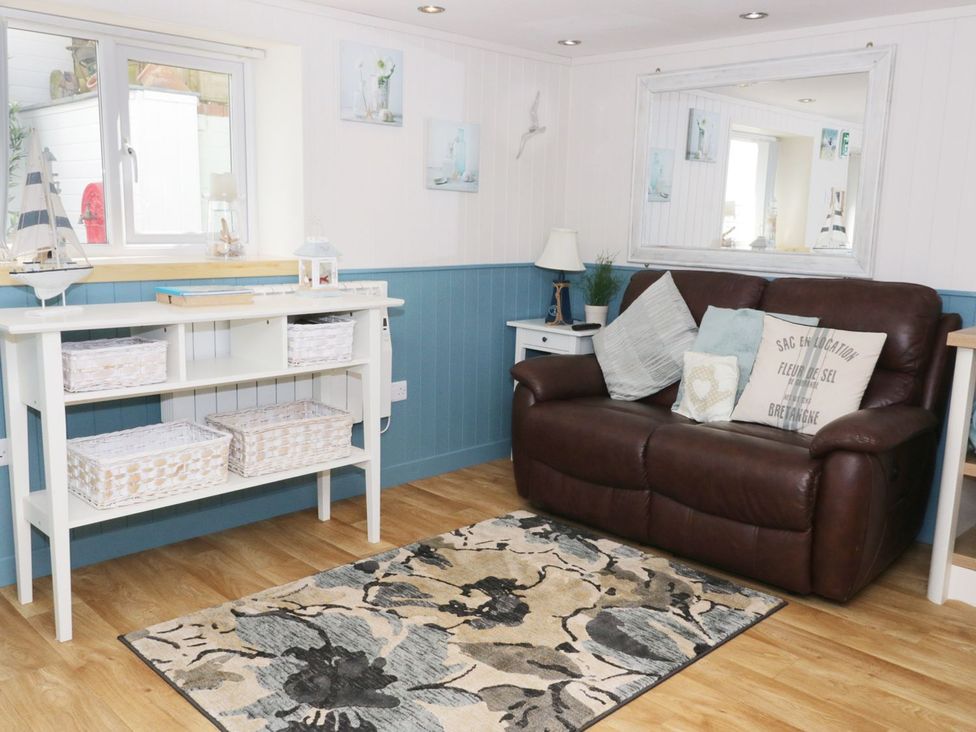 A living room with a sofa and table at The Hideaways in Tyn-y-Gongl
