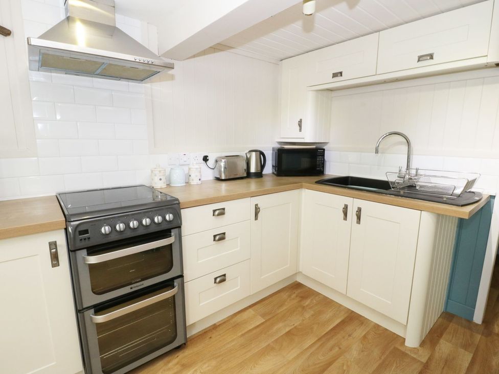 A kitchen with stove, oven, sink, and microwave at The Hideaways Tyn-y-Gongl