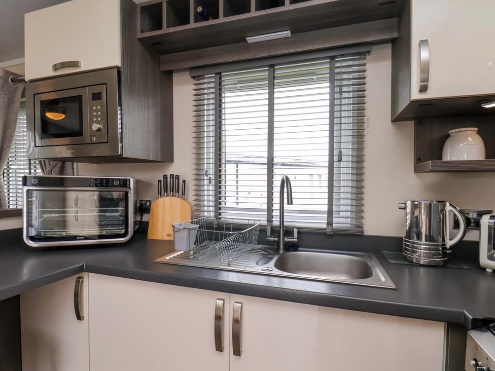 A kitchen with a microwave, oven, sink and dish rack at Finch 66 in Scarborough