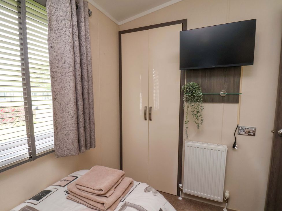 A bedroom with a television and towels on the bed at Finch 66 in Scarborough