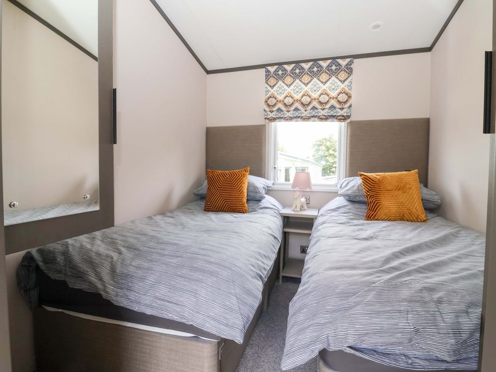 A bedroom with two beds and a lamp on a nightstand at Lodge - Plot 18 Near Sherburn