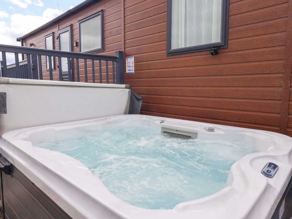 A hot tub beside a wooden cabin at Lodge - Plot 18 Near Sherburn