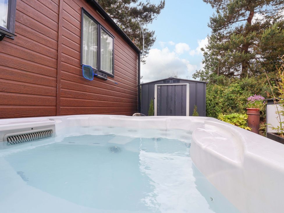 A hot tub with a shed and surrounding plants at Lodge - Plot 18 Near Sherburn