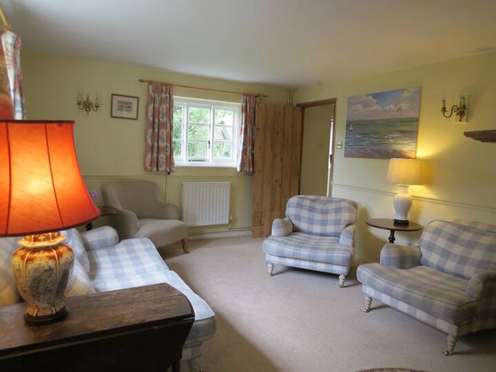 A living room with checkered sofas and a lamp at Little Owl High Cross near Petersfield