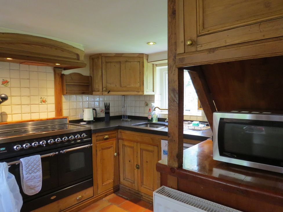 A kitchen with wood cabinets and appliances at Little Owl in High Cross near Petersfield