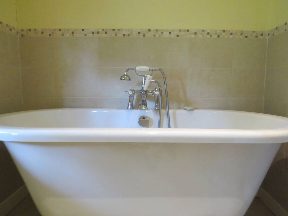 A bathtub with a faucet in the bathroom at Little Owl High Cross near Petersfield