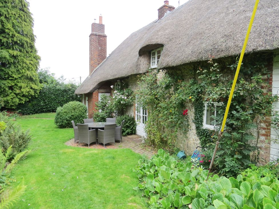 A garden with a thatched house and outdoor furniture at Little Owl High Cross near Petersfield