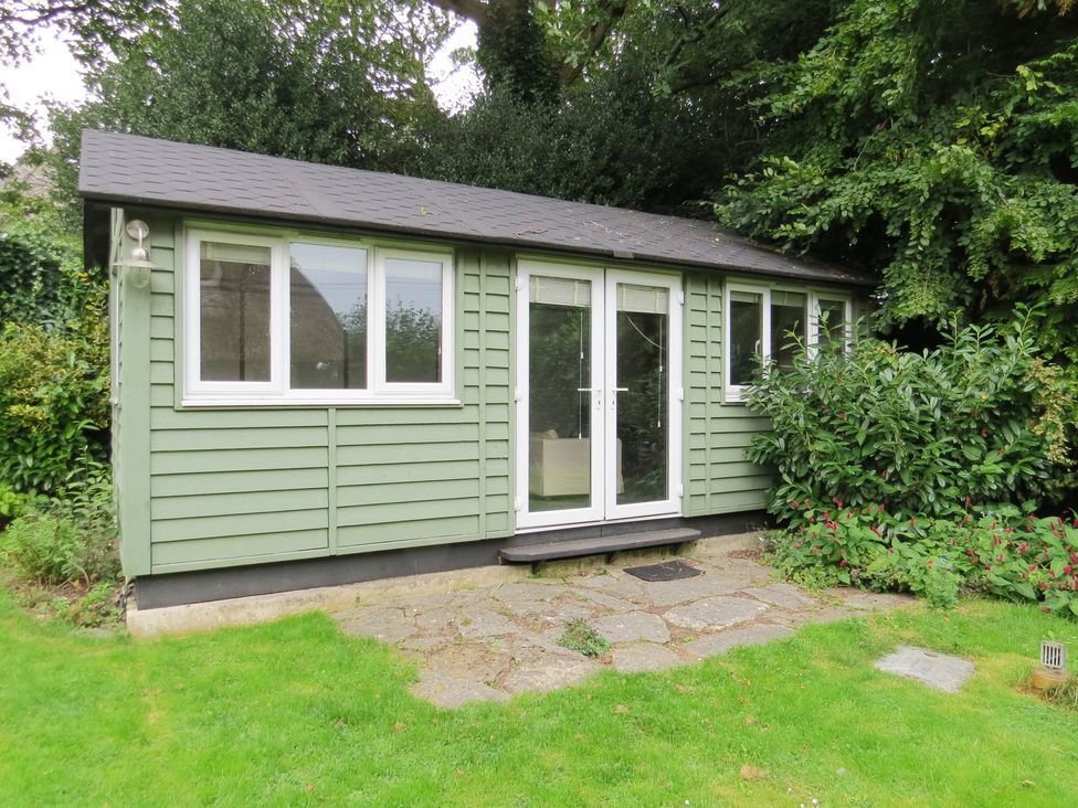 A garden room with windows and a door at Little Owl in High Cross near Petersfield
