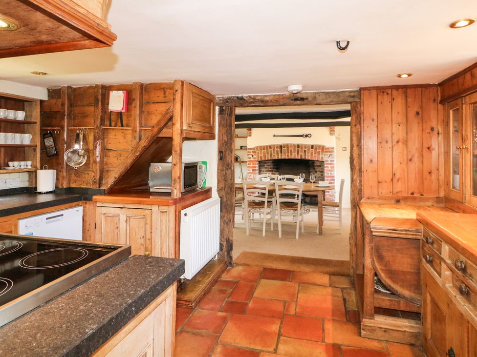 A kitchen with wooden cabinets and a dining area at Little Owl High Cross near Petersfield