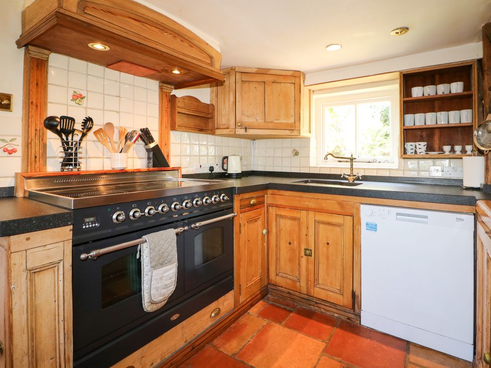 A kitchen with wooden cabinets and cooking appliances at Little Owl High Cross near Petersfield