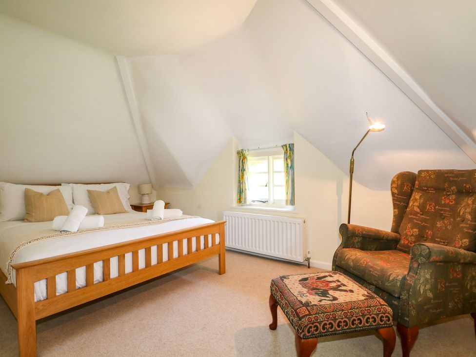 A bedroom with a bed and an armchair at Little Owl High Cross near Petersfield