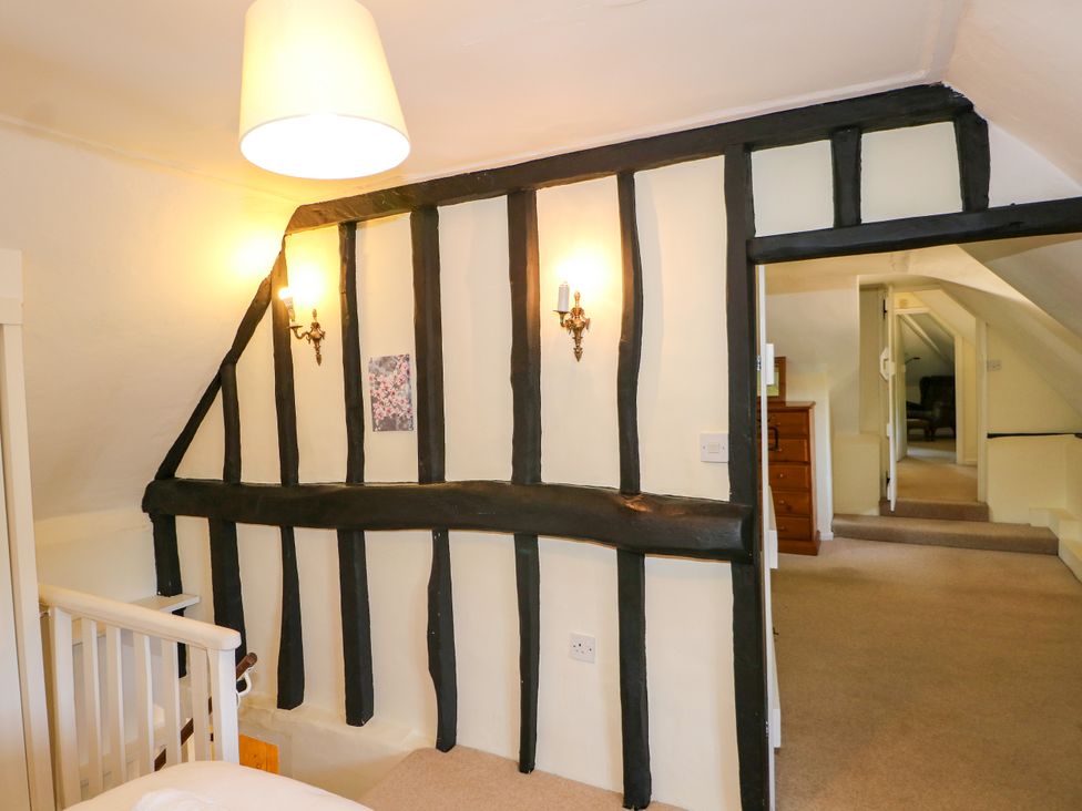 A hallway with a staircase and wall sconces at Little Owl in High Cross near Petersfield