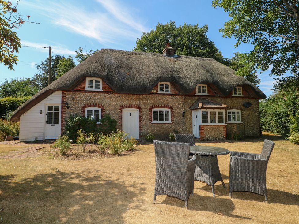 A cottage with a thatched roof and outdoor furniture at Little Owl in High Cross near Petersfield