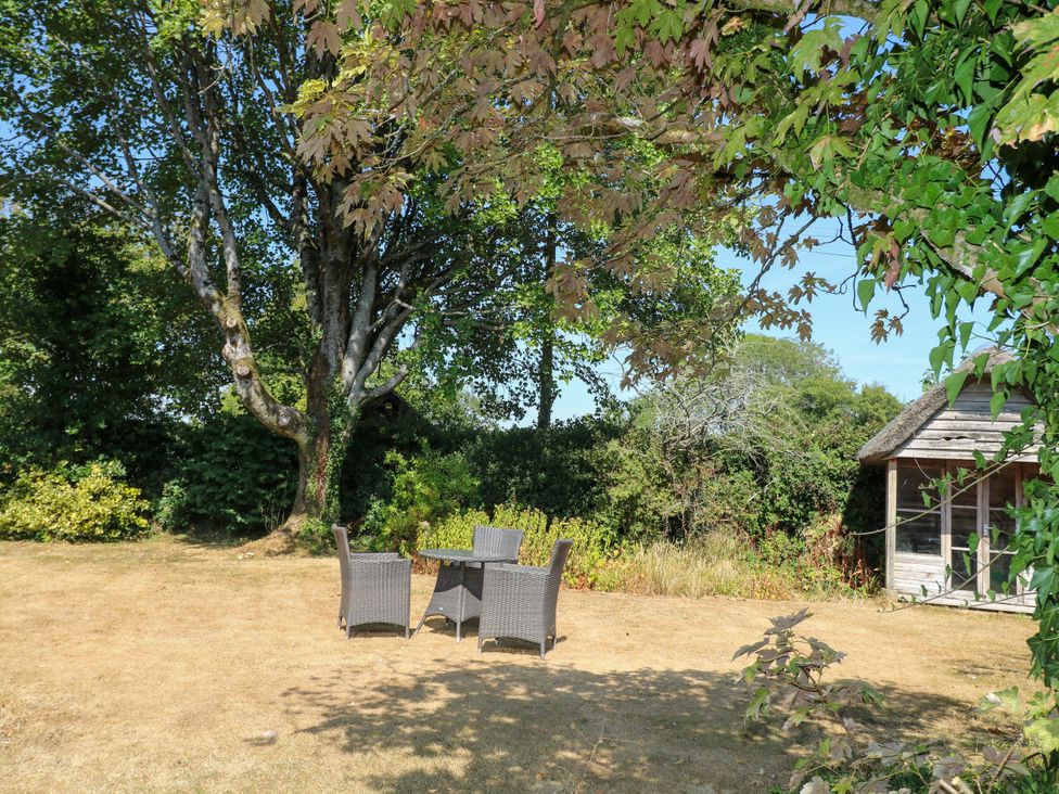 A garden with a table and chairs under a tree at Little Owl in High Cross near Petersfield