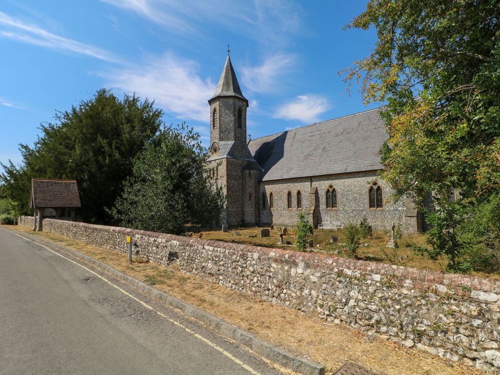 A church with a stone wall and road in front at Little Owl High Cross near Petersfield
