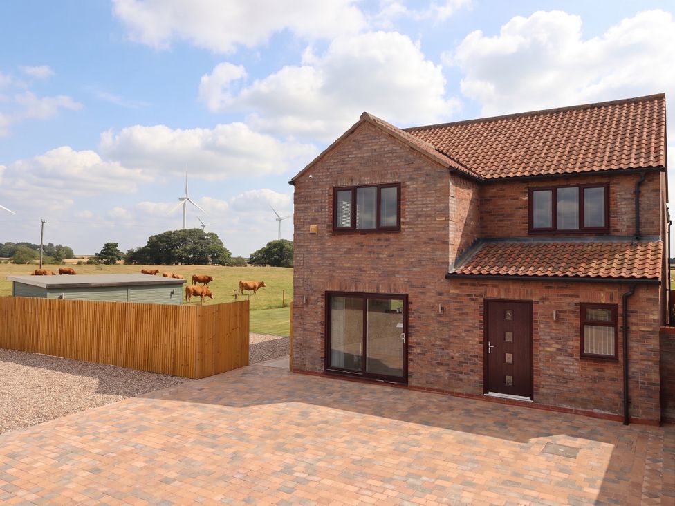 A house with a driveway and cows in a field at Gravel Pit Cottage Bridlington