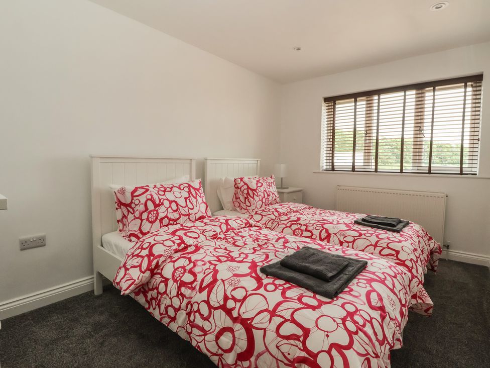 A bedroom with two beds and window at Gravel Pit Cottage in Bridlington