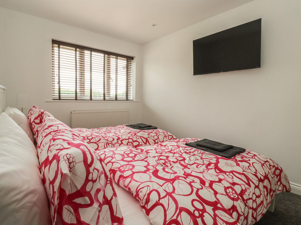 A bedroom with two beds and a television at Gravel Pit Cottage in Bridlington