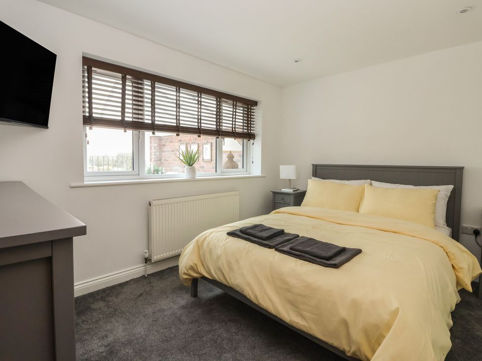 A bedroom with a bed and a nightstand at Gravel Pit Cottage in Bridlington