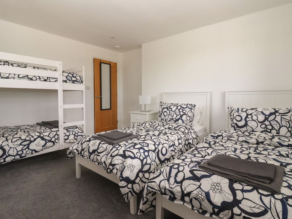 A bedroom with a bunk bed and two single beds at Gravel Pit Cottage in Bridlington