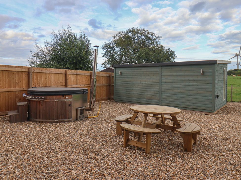 An outdoor area with a hot tub and picnic table at Gravel Pit Cottage in Fraisthorpe