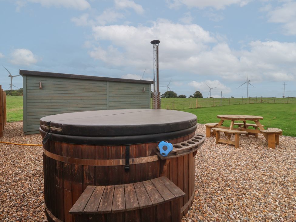An outdoor garden with a hot tub and picnic table at Gravel Pit Cottage in Fraisthorpe