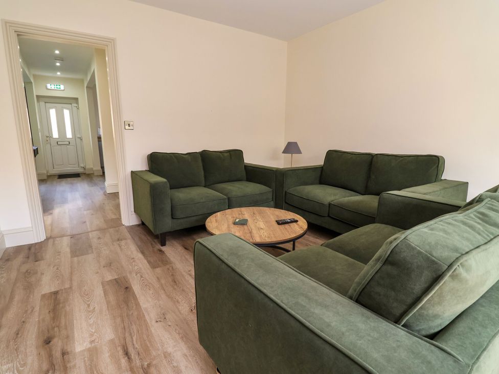A living room with green sofas and a coffee table at 2 Rookery Close in Nantwich