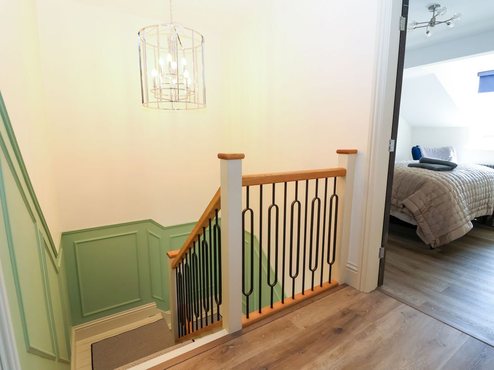 A staircase with a chandelier and wall paneling at 2 Rookery Close, Nantwich