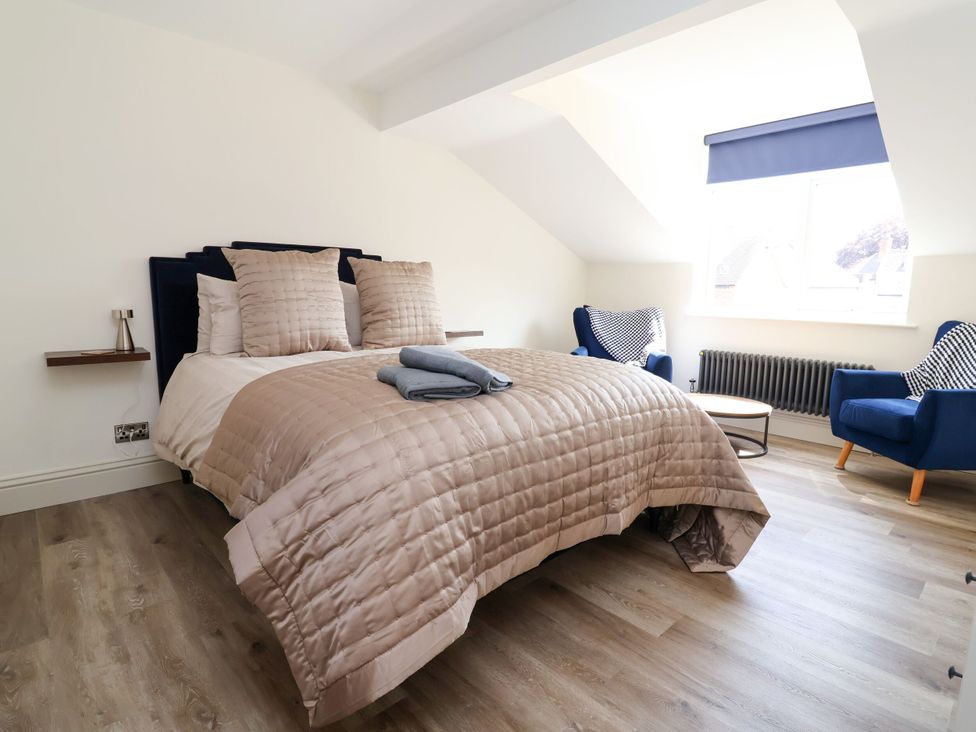 A bedroom with a bed and two armchairs at 2 Rookery Close in Nantwich