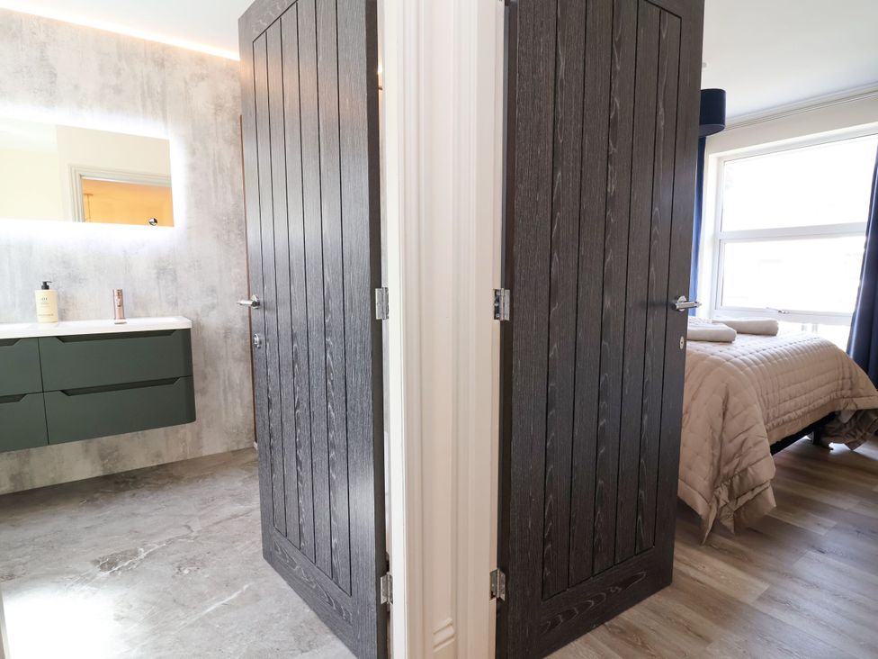 A bathroom with a sink and a door leading to a bedroom at 2 Rookery Close in Nantwich