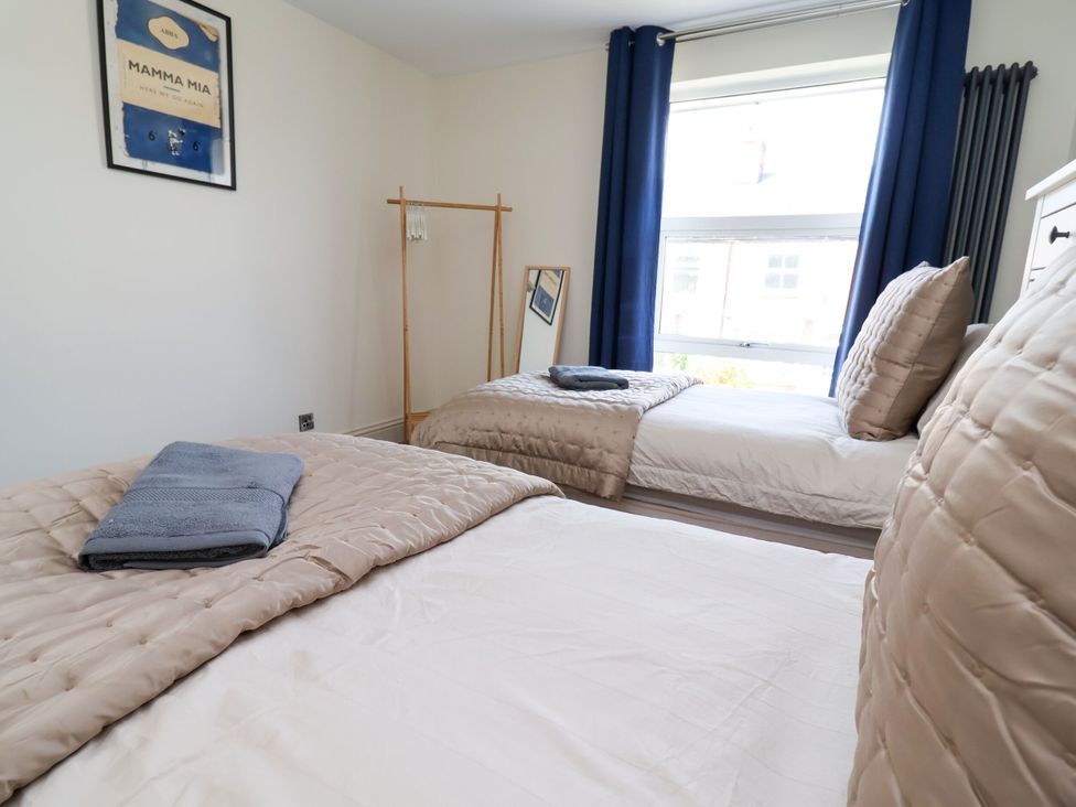 A bedroom with two beds and a mirror at 2 Rookery Close in Nantwich
