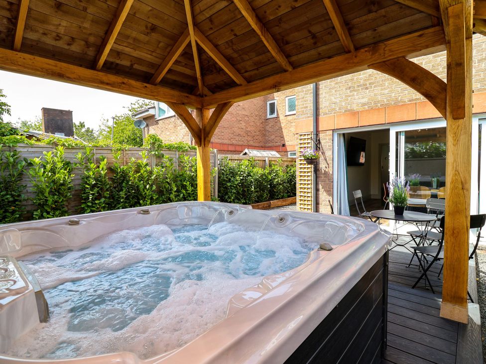 A hot tub under a wooden structure in an outdoor area at 2 Rookery Close Nantwich