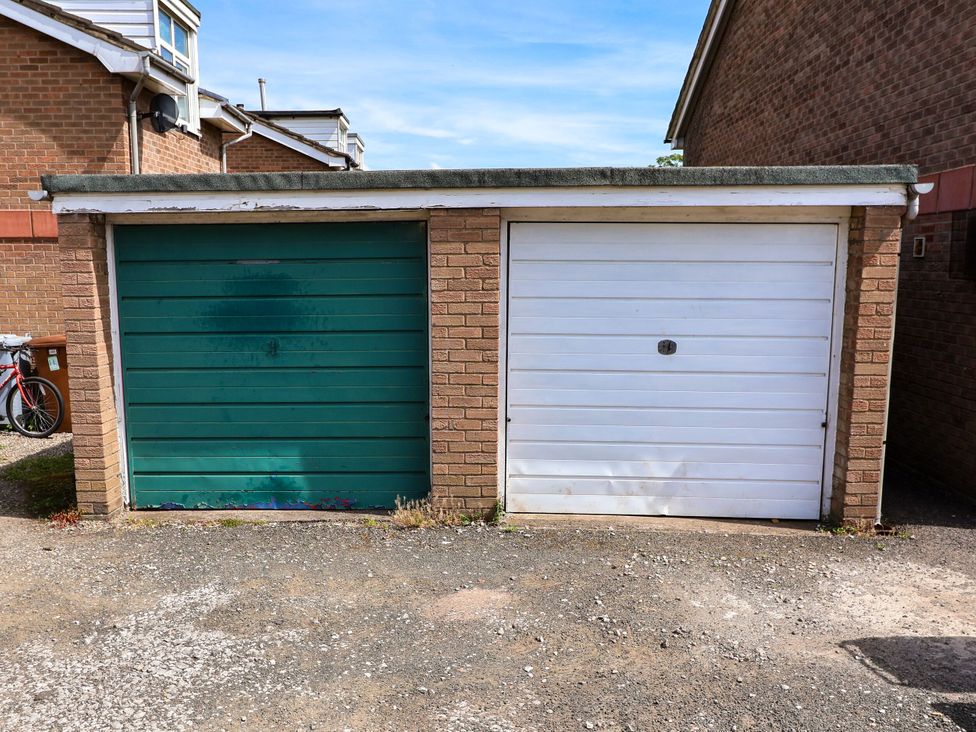 Two garages with one green and one white door at 2 Rookery Close in Nantwich
