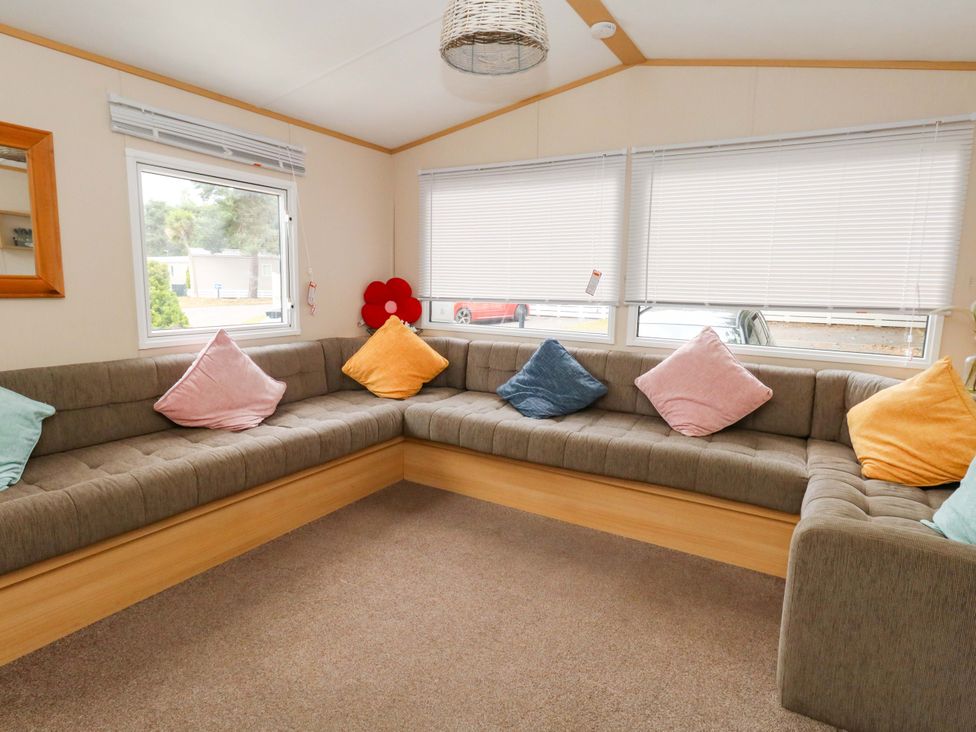 A snug with a corner sofa and cushions at Foxglove 4 Ringwood