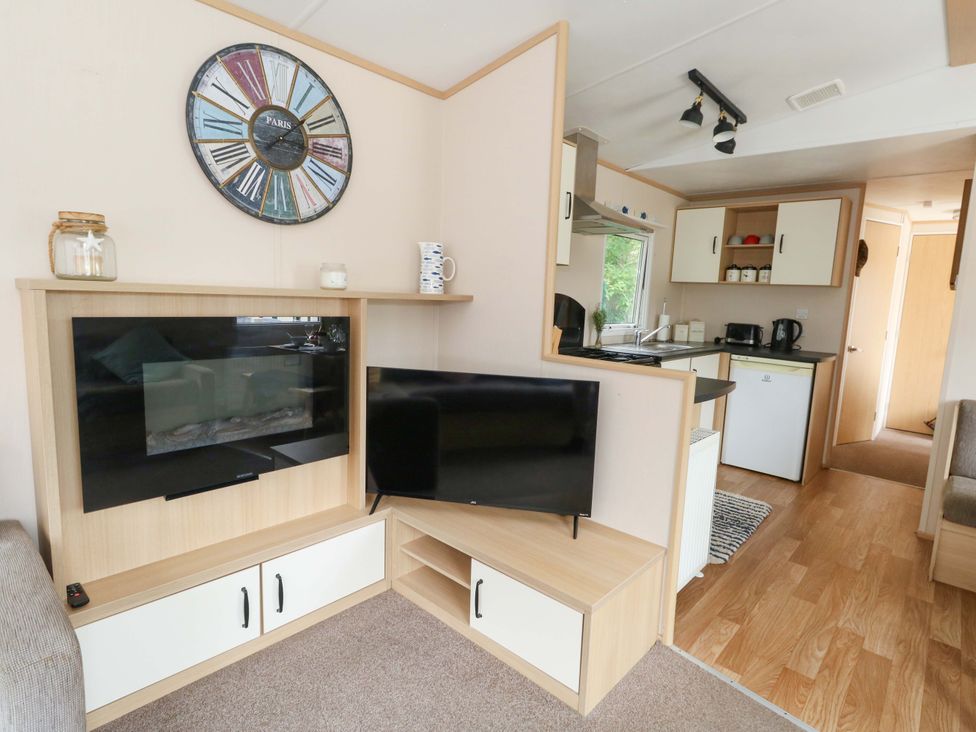 A living room with a television and kitchen area at Foxglove 4 in Ringwood