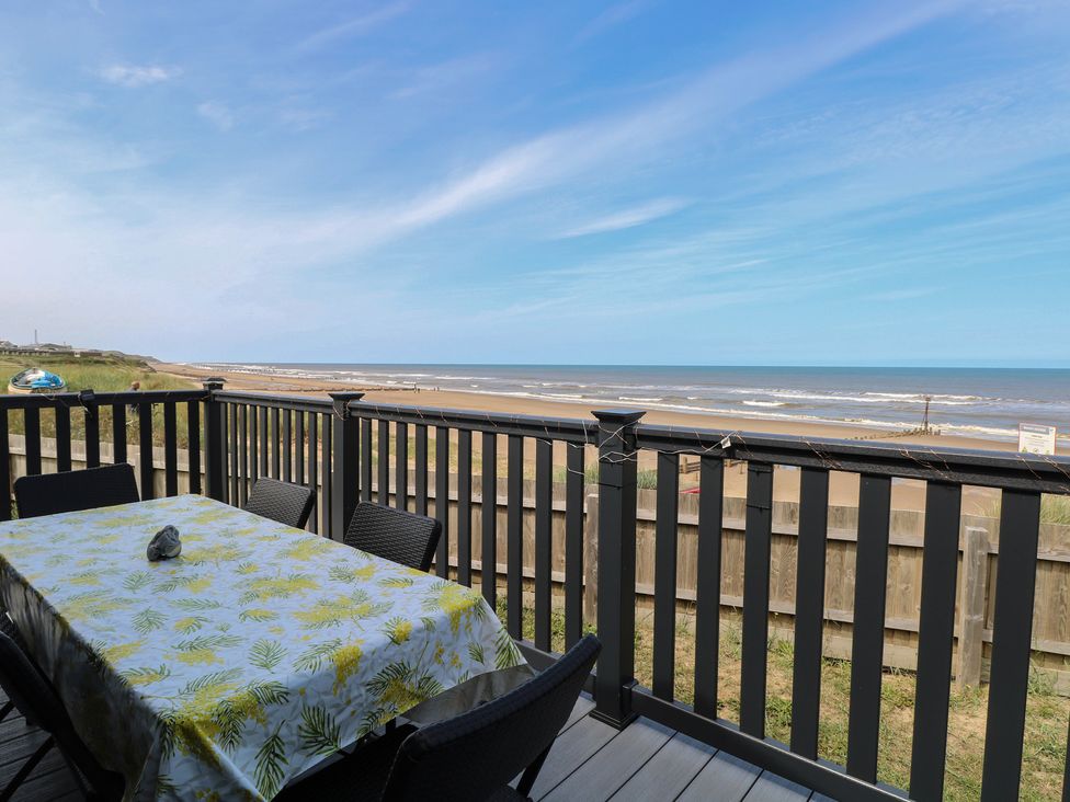 A deck with a table and chairs overlooking the ocean at Plot 34 in Bacton