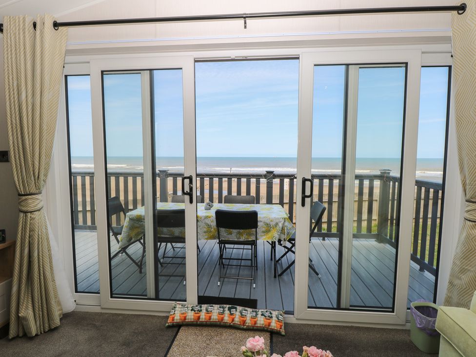 A dining area with a table and chairs overlooking the sea at Plot 34 Bacton