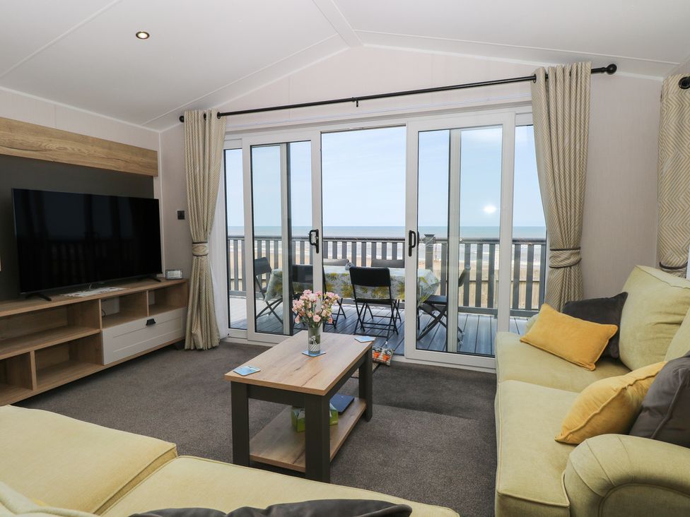 A living room with a television and a sliding door at Plot 34 Bacton