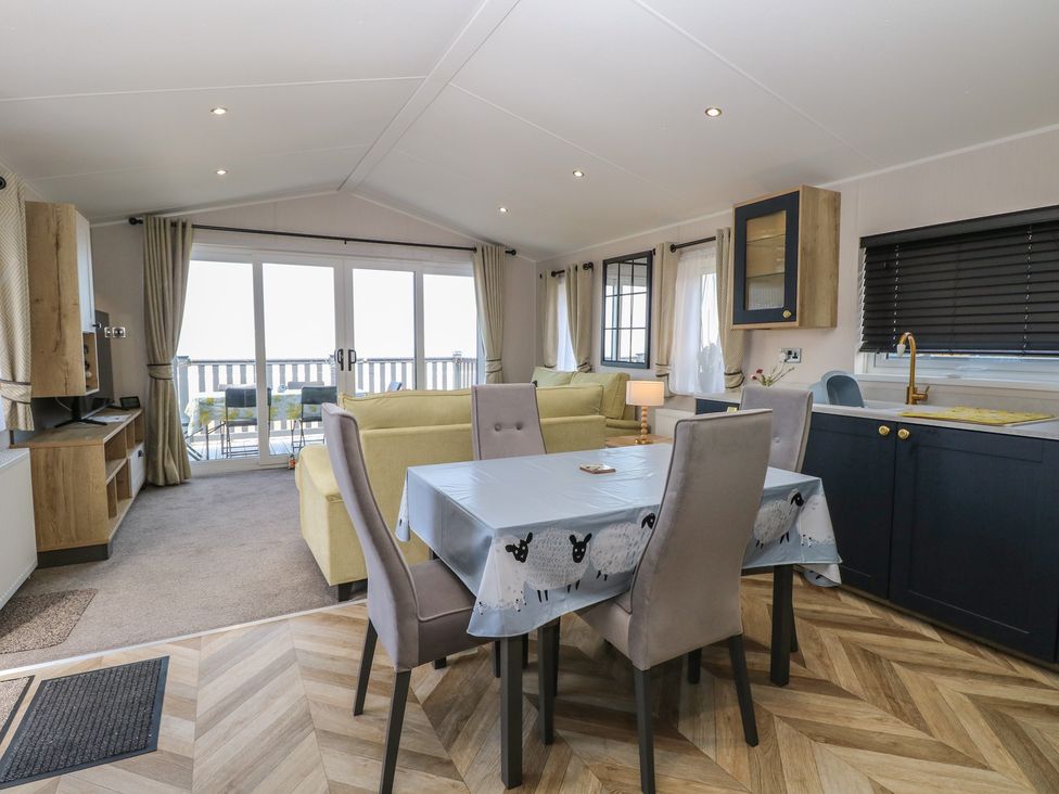 A living room with a sofa and dining area at Plot 34 Bacton
