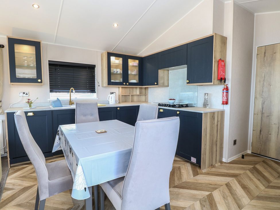 A kitchen with cabinets and a dining table at Plot 34 in Bacton
