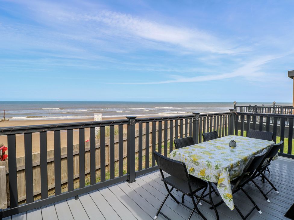 An outdoor dining area with a table and chairs overlooking the sea at Plot 34 Bacton