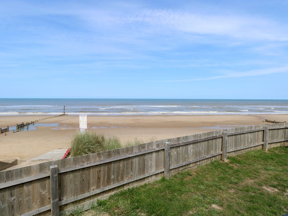 A beach with a fence and a sign at Plot 34 Bacton