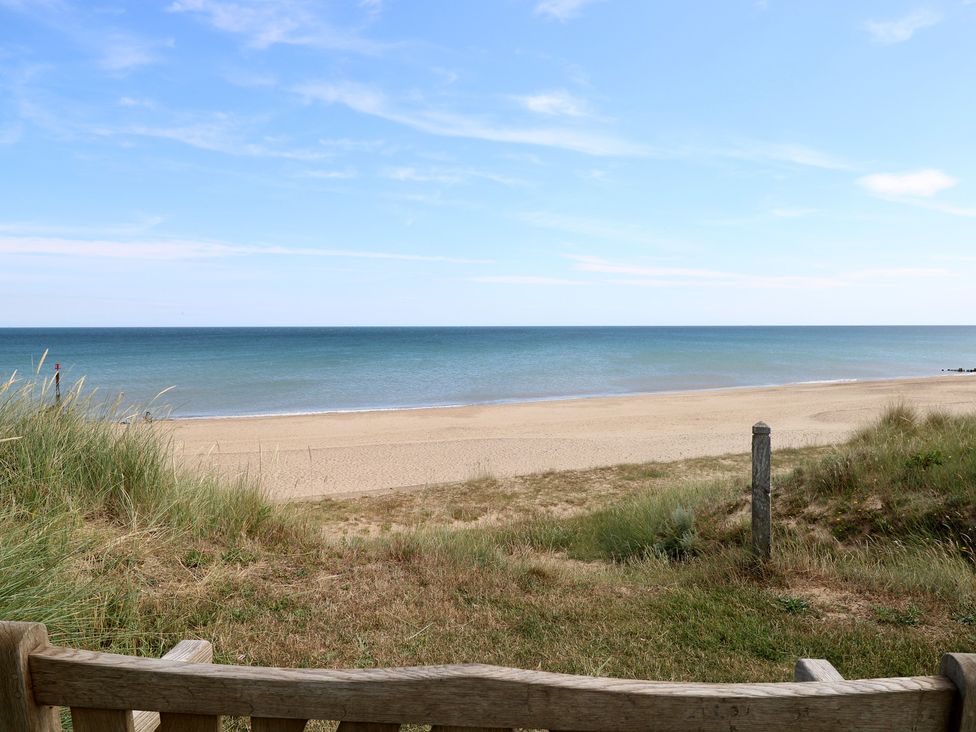 A beach view with grass and a bench at Plot 34 in Bacton